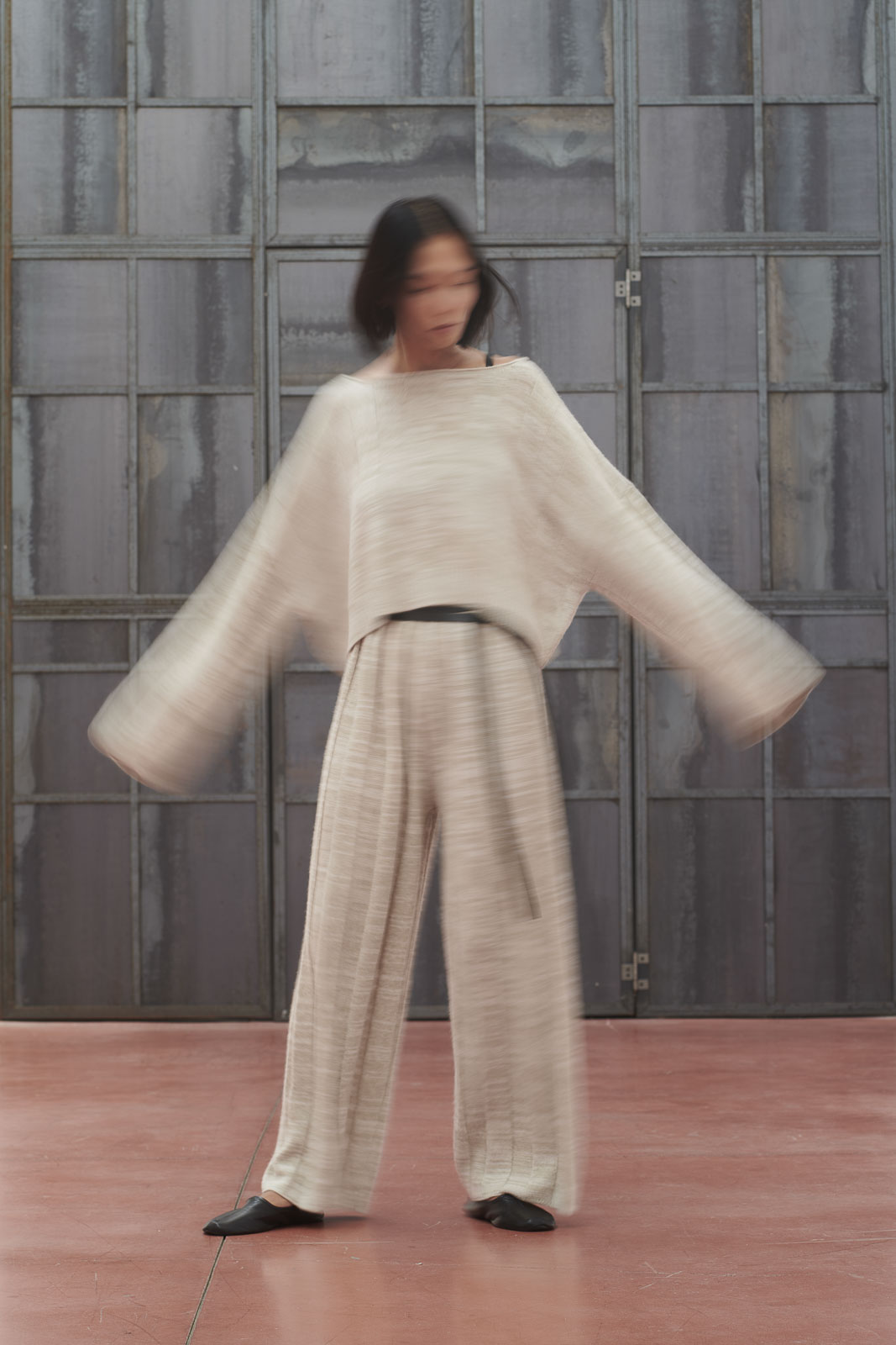 woman dressing a knitwear cashmere dress, waving her arms 